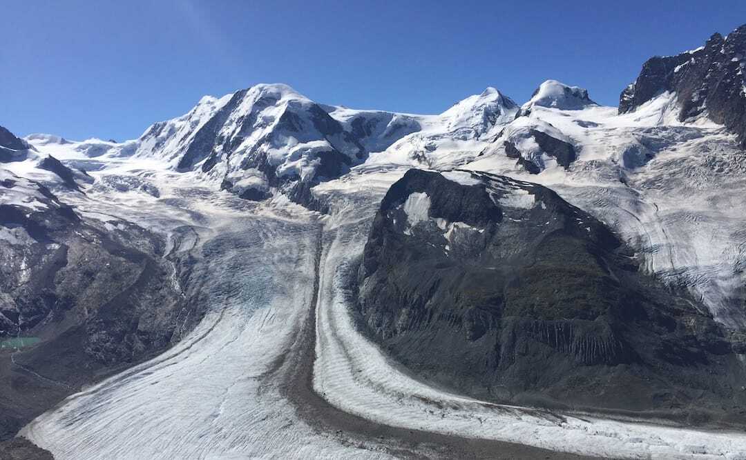 The Gornergletscher Glacier in Zermatt, snow covered mountains and a bright blue sky.