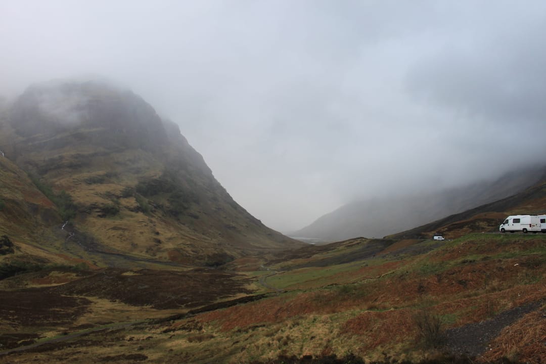 The van is parked in the car park with the dramatic Three Sisters rocks in the background