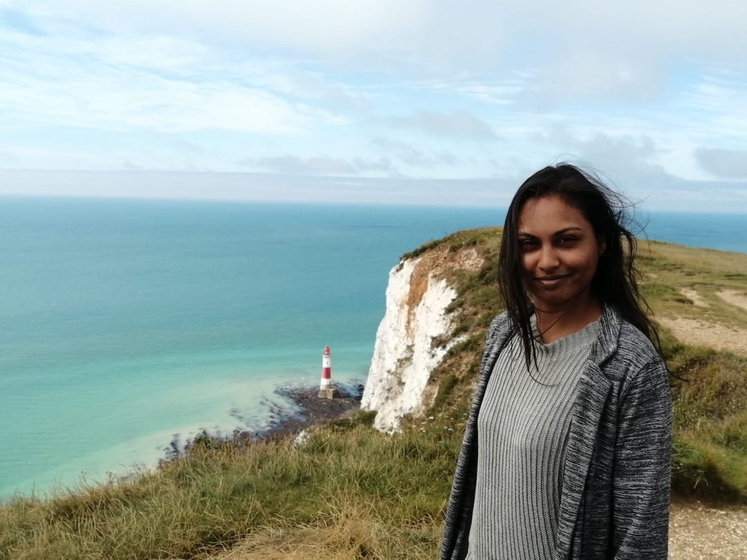 Sunita, a young woman of Mauritian heritage, stands at the top of the chalk sea cliff at Beachy Head.