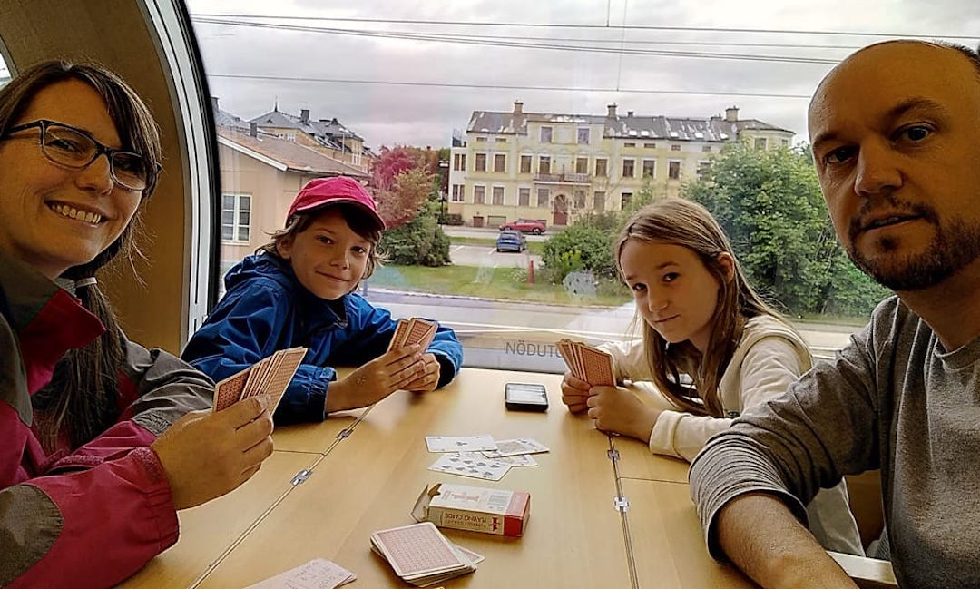 Four people sitting around a train table playing cards