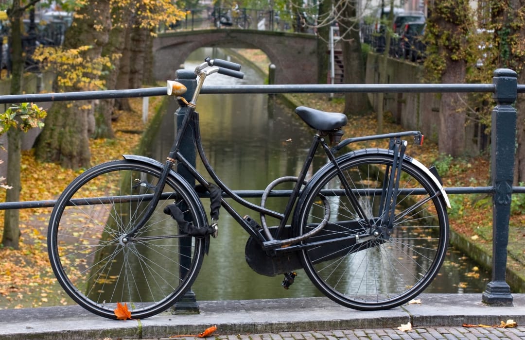 Image shows a bicycle leaning against the railings of a low-level canal in Utrecht